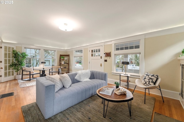 living area with visible vents, light wood-style flooring, and baseboards