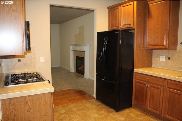 kitchen with tasteful backsplash, stainless steel gas stovetop, and black fridge