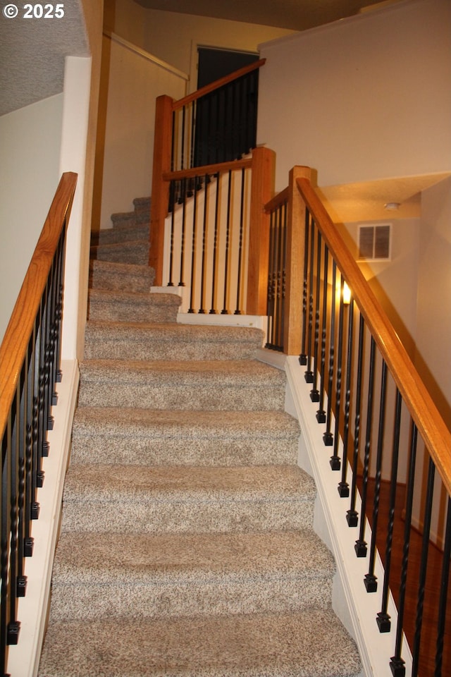 stairway featuring a textured ceiling