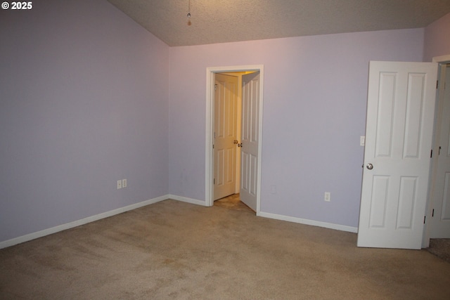 spare room with lofted ceiling, light carpet, and a textured ceiling