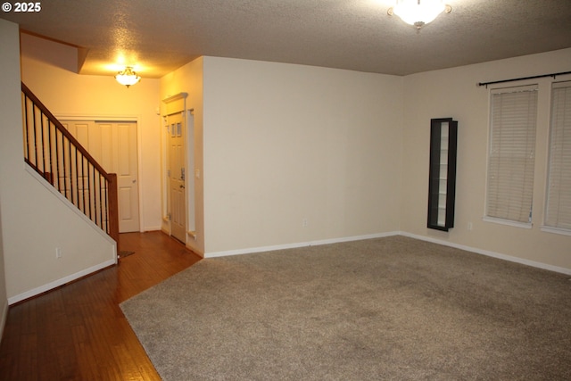 unfurnished room with dark hardwood / wood-style flooring and a textured ceiling