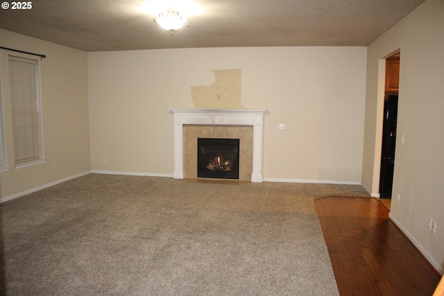 unfurnished living room featuring carpet, a tile fireplace, and a textured ceiling