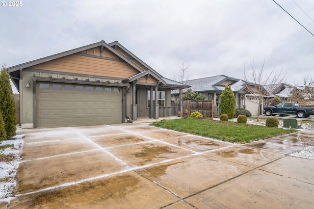 view of front of home featuring board and batten siding, driveway, an attached garage, and fence