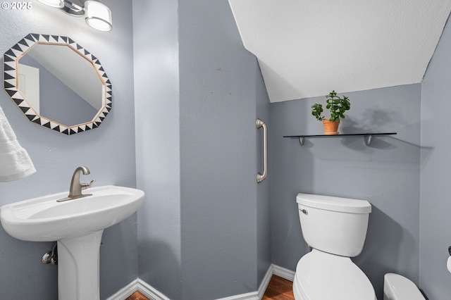 bathroom with toilet, baseboards, and wood finished floors