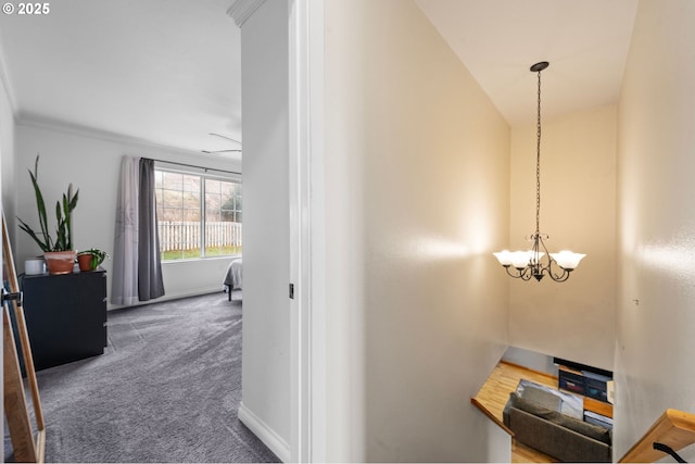 hall with carpet floors, baseboards, and an inviting chandelier