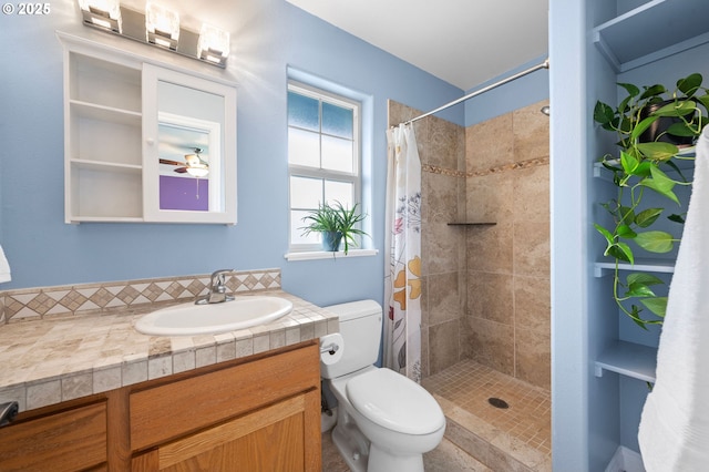 bathroom with tiled shower, vanity, toilet, and a ceiling fan