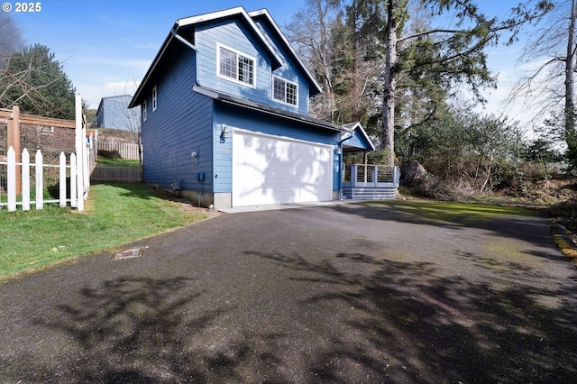 view of home's exterior with driveway, a lawn, an attached garage, covered porch, and fence