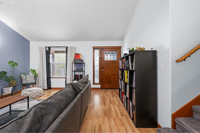 living room with stairs, baseboards, lofted ceiling, and light wood-style floors