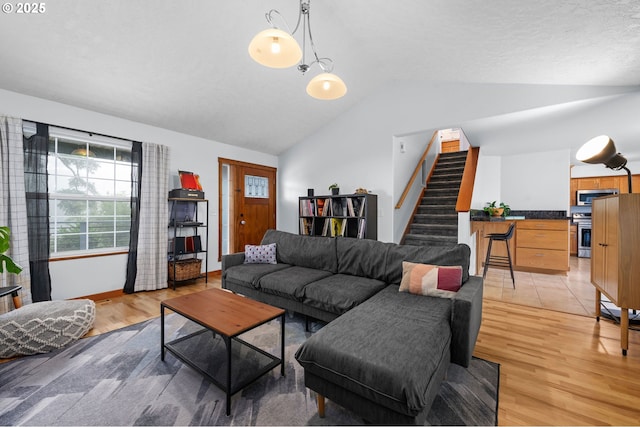 living room featuring light wood-style flooring, stairway, vaulted ceiling, and baseboards