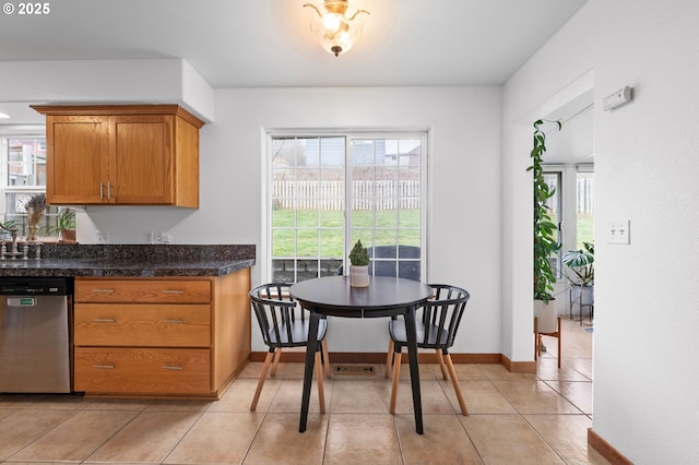 kitchen with a wealth of natural light, brown cabinets, stainless steel dishwasher, and light tile patterned flooring