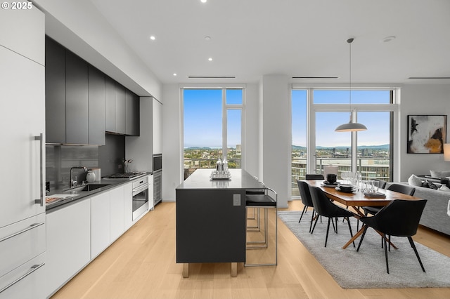 kitchen with a center island, sink, light hardwood / wood-style flooring, expansive windows, and decorative light fixtures