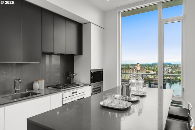 kitchen featuring decorative backsplash, wall oven, sink, a water view, and stainless steel gas stovetop