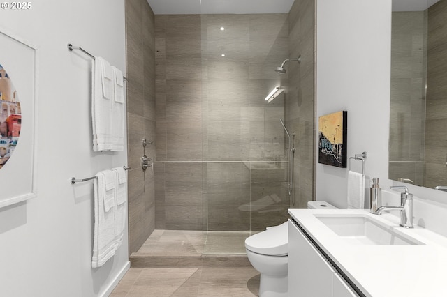 bathroom featuring vanity, toilet, and a tile shower