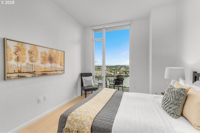 bedroom featuring a water view, wood-type flooring, a wall of windows, and access to outside