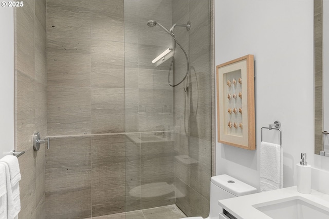 bathroom with a tile shower, vanity, and toilet