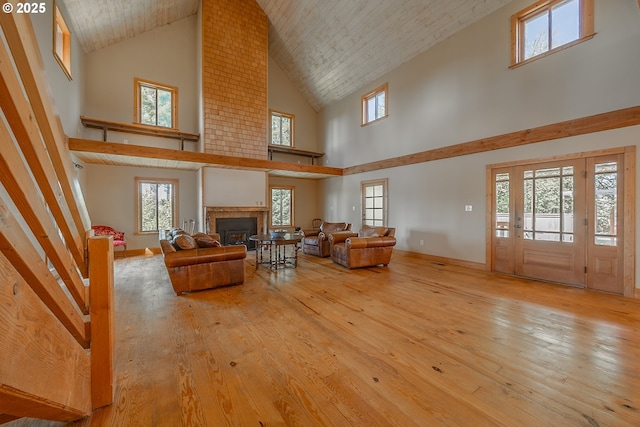 living area with high vaulted ceiling, a wealth of natural light, hardwood / wood-style floors, and a fireplace