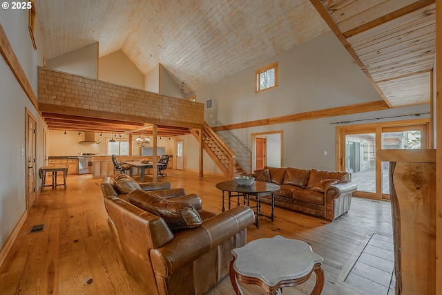 living room with visible vents, stairs, high vaulted ceiling, and wood-type flooring