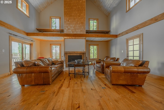 living area with a fireplace, high vaulted ceiling, wooden ceiling, and light wood-style floors