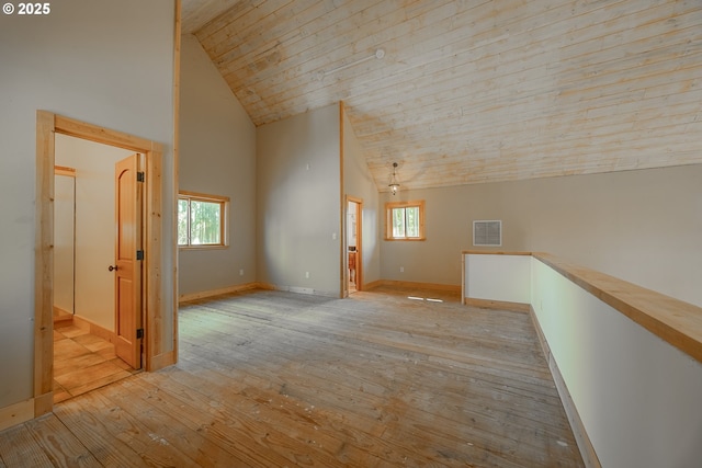 additional living space featuring high vaulted ceiling, plenty of natural light, light wood-style flooring, and visible vents