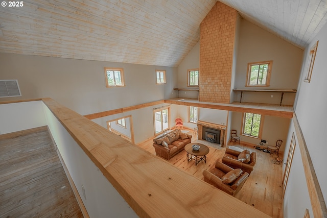 living room featuring high vaulted ceiling, visible vents, a fireplace with flush hearth, and hardwood / wood-style flooring