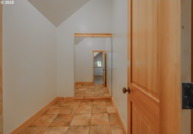 hall featuring baseboards and vaulted ceiling