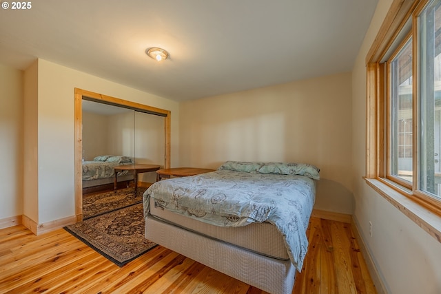bedroom with a closet, baseboards, and light wood-type flooring