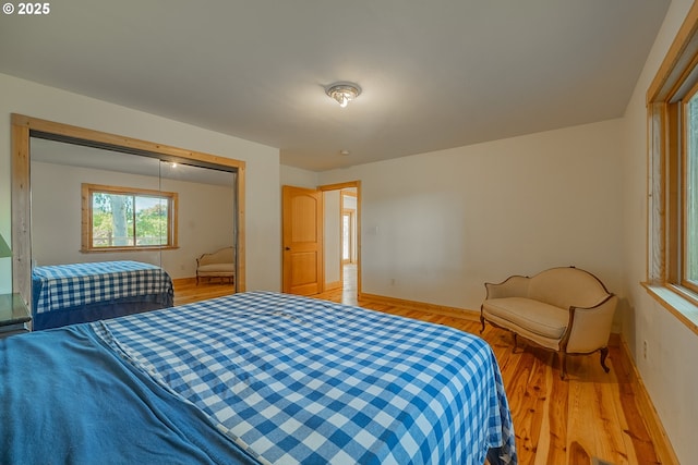 bedroom with a closet, baseboards, and light wood-type flooring