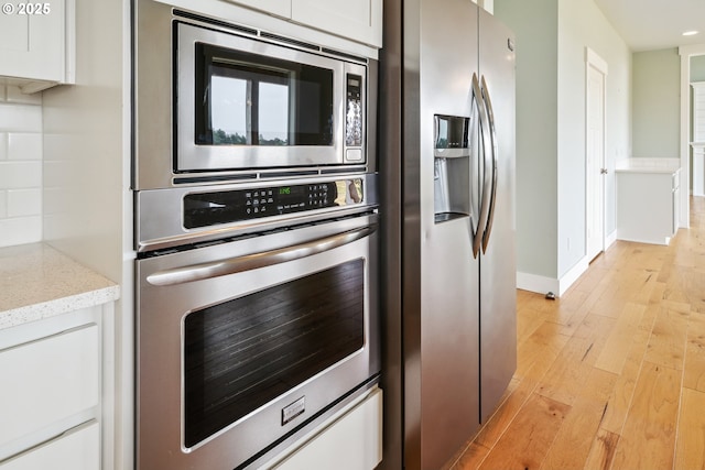 80654 Polo Ridge Rd, Warrenton, OR 97146 - kitchen with appliances with stainless steel finishes, light wood-type flooring, light stone counters, white cabinets, and recessed lighting