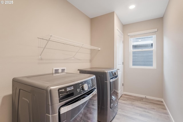 laundry area with washer and clothes dryer and light wood-type flooring