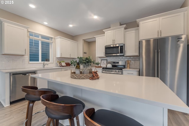 kitchen with white cabinetry, a kitchen island, stainless steel appliances, and light wood-type flooring