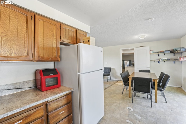 534 N 11th St, Saint Helens, OR 97051 - kitchen with freestanding refrigerator, a textured ceiling, brown cabinets, light countertops, and light flooring
