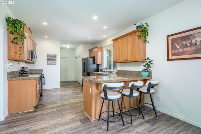 616 E 13th Pl, Lafayette, OR 97127 - kitchen featuring black appliances, a peninsula, light wood-style flooring, a kitchen bar, and recessed lighting