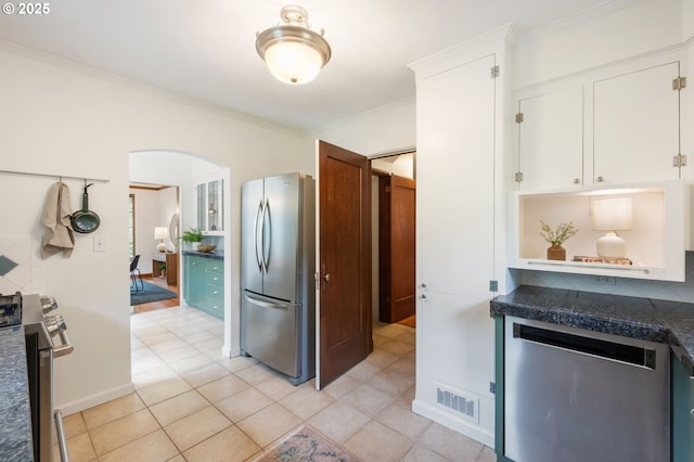 6040 SE 32nd Ave, Portland, OR 97202 - kitchen featuring stainless steel appliances, dark countertops, arched walkways, white cabinets, and ornamental molding