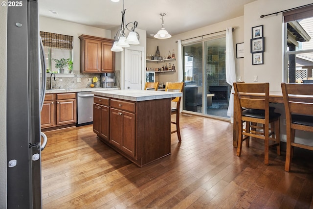 19459 Leland Rd, Oregon City, OR 97045 - kitchen featuring appliances with stainless steel finishes, light countertops, hardwood / wood-style flooring, tasteful backsplash, and brown cabinets