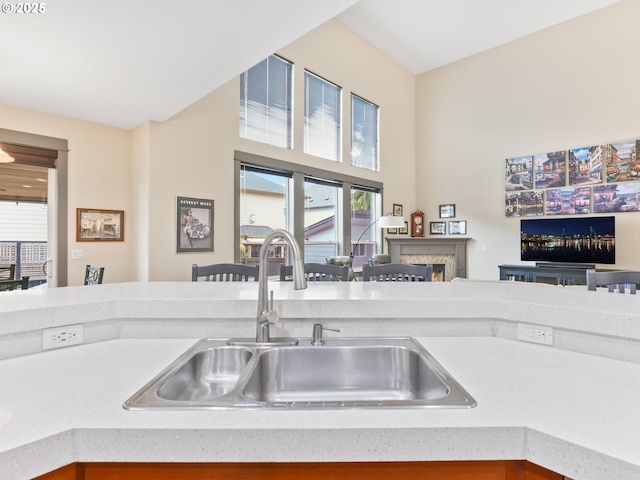 kitchen with a sink, open floor plan, light countertops, and a lit fireplace