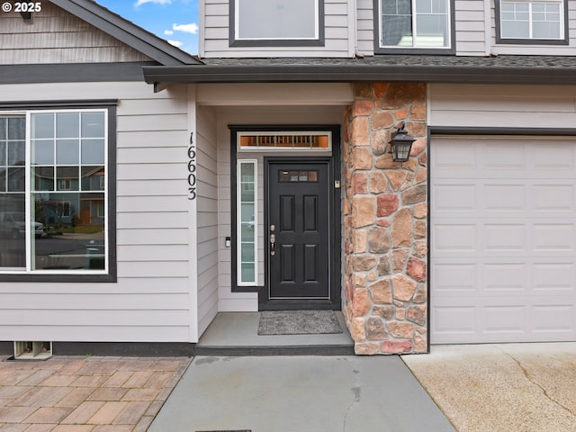 doorway to property with a garage and stone siding