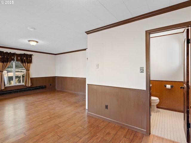 unfurnished room with light hardwood / wood-style floors, a baseboard radiator, and crown molding