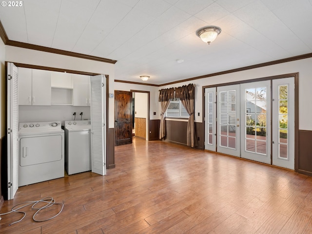 clothes washing area with washer and clothes dryer, cabinets, wooden walls, ornamental molding, and light hardwood / wood-style flooring