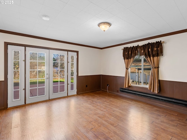 empty room featuring a wealth of natural light, crown molding, light hardwood / wood-style floors, and a baseboard radiator