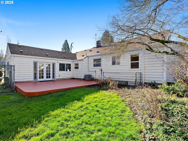 back of property with central AC unit, french doors, a patio, and a yard