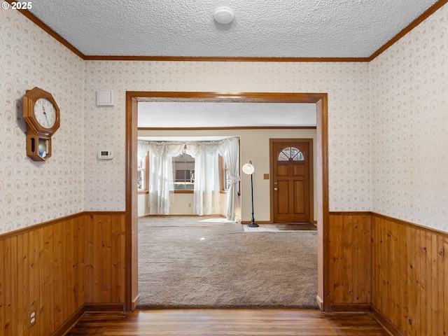 hall with a textured ceiling, ornamental molding, and hardwood / wood-style flooring