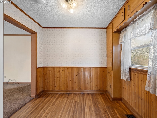 unfurnished room featuring dark wood-type flooring, a textured ceiling, and ornamental molding