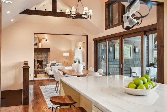 kitchen featuring an inviting chandelier, dark wood-style flooring, beam ceiling, recessed lighting, and light stone counters