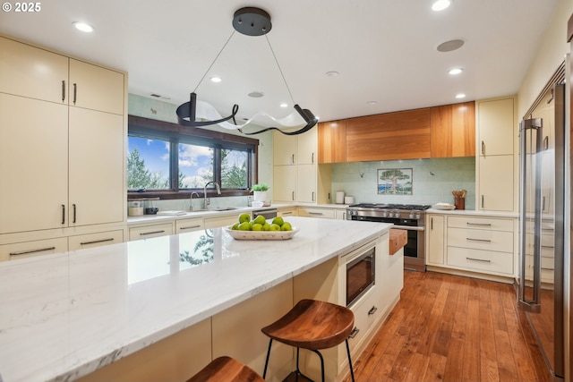 kitchen featuring light stone countertops, tasteful backsplash, recessed lighting, a breakfast bar, and appliances with stainless steel finishes