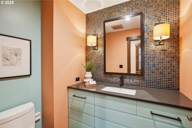 half bath with vanity, visible vents, backsplash, and toilet