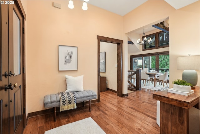 sitting room with baseboards, a chandelier, wood finished floors, and a high ceiling