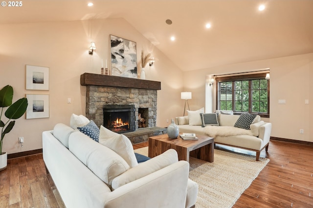 living room with high vaulted ceiling, wood-type flooring, a stone fireplace, and baseboards