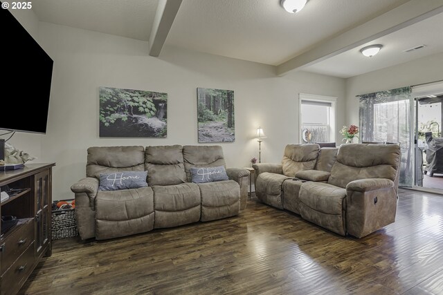 living area featuring visible vents, dark wood-type flooring, and beam ceiling