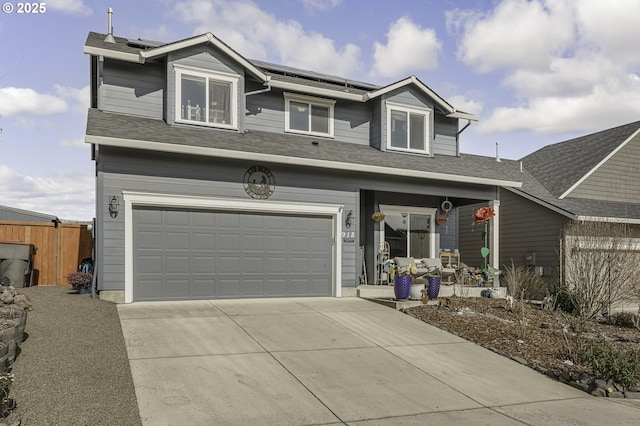 traditional home with a garage, roof mounted solar panels, driveway, and fence