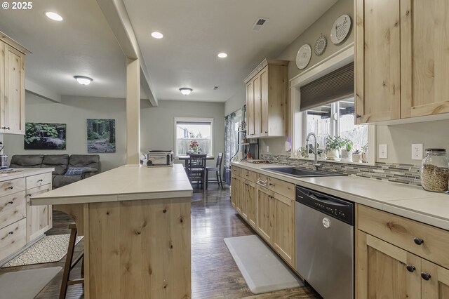 kitchen featuring a sink, stainless steel dishwasher, light brown cabinets, and a wealth of natural light